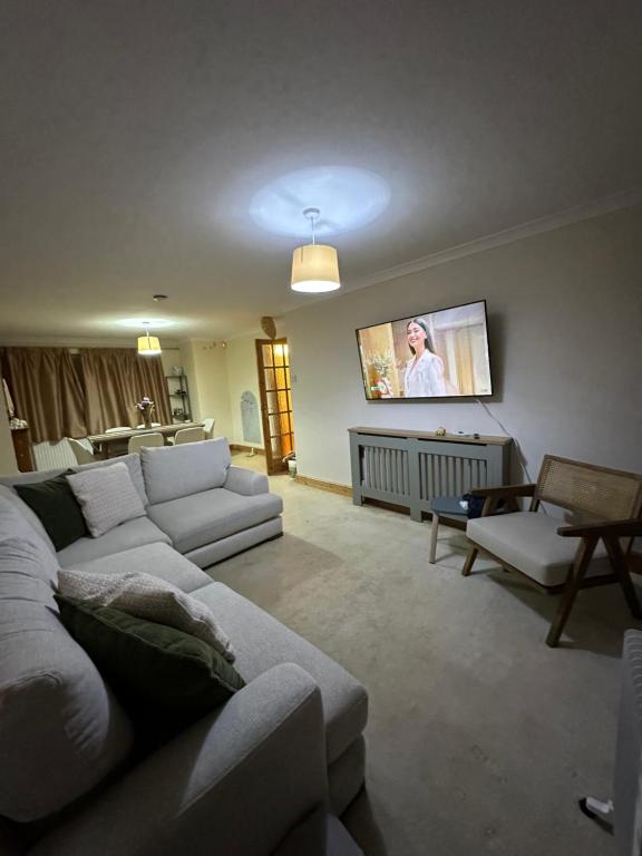 a living room with a couch and a flat screen tv at Spacious 3 bed semi-detached house in Luton