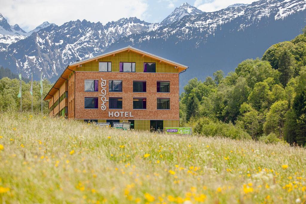 a hotel in a field with mountains in the background at Explorer Hotel Montafon in Gaschurn
