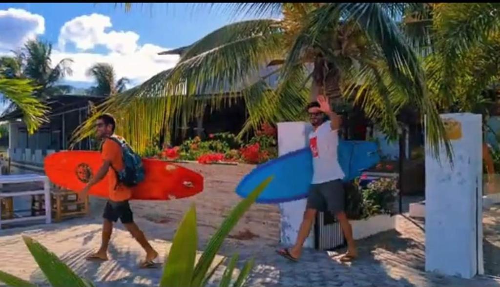 two men walking on the beach with their surfboards at Panorama Ekas in Ekas