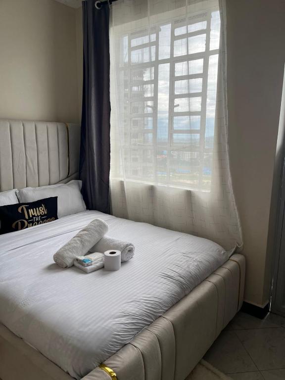 a bed with two towels and a cup and a window at Maple Lane Stays in Nakuru