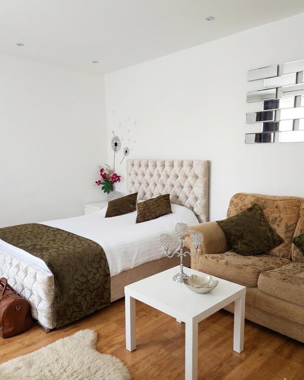 a bedroom with a bed and a couch and a table at Modern Studio Near Gatwick in London Gatwick Airport