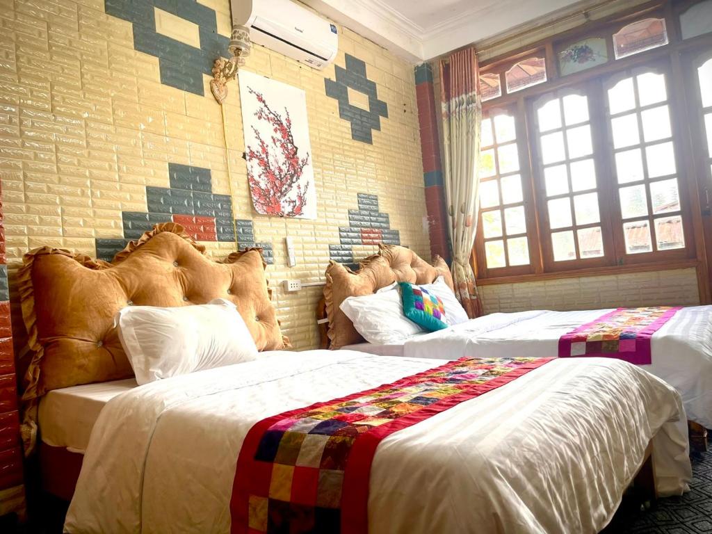 a bedroom with two beds and a brick wall at SUN Homestay sa pa in Sapa