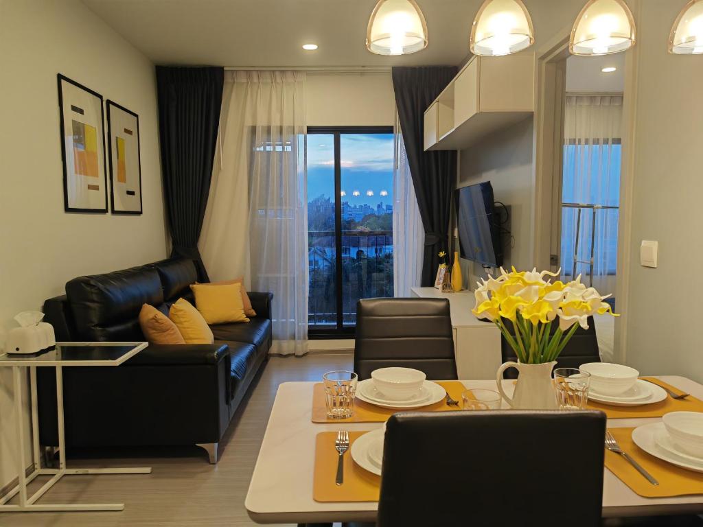a living room with a couch and a table with yellow flowers at Cozy Breeze Onnut 21 in Amphoe Phra Khanong