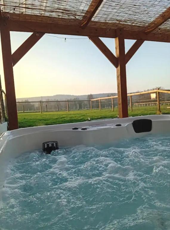 a jacuzzi tub with a view of a field at Gîte avec jacuzzi privatif et piscine privative - Haras Le Val Du Conte in Le Bouillon