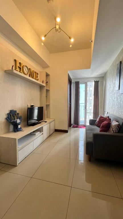 a living room with a couch and a tv at Vida View Apartment by Vida Connect in Makassar