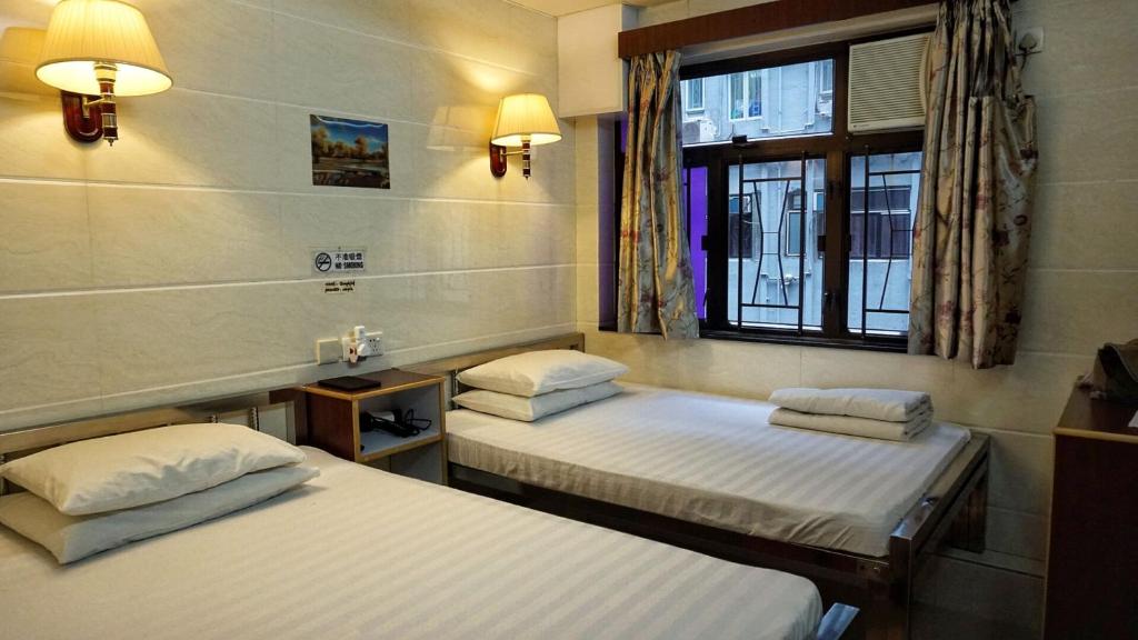 2 camas individuales en una habitación con ventana en Maple Leaf Guest House, en Hong Kong