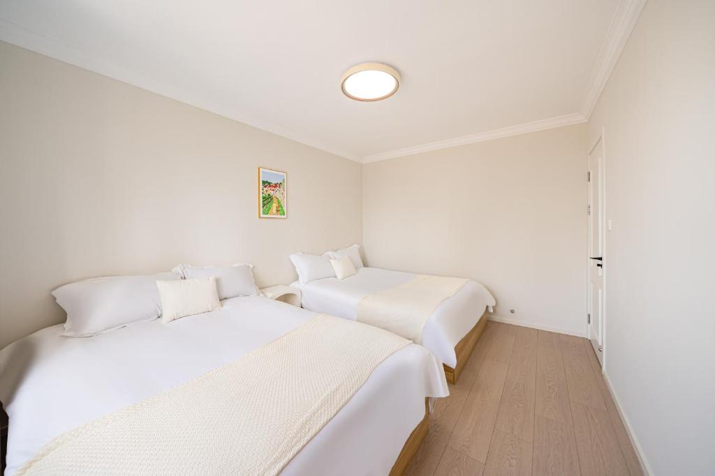 two beds in a room with white walls at Today-Lujiazui Riverside,Bund Riverview in Shanghai