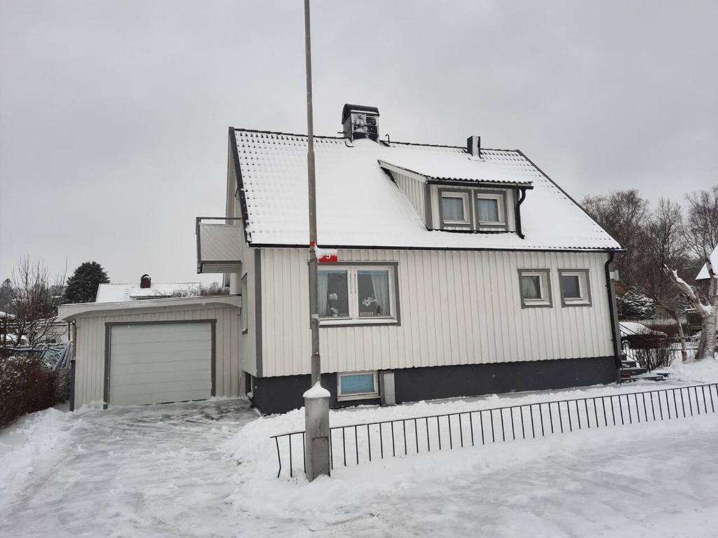 a house is covered in snow with a fence at Workers Stay - Housing for Workers Volvo Torslanda in Gothenburg