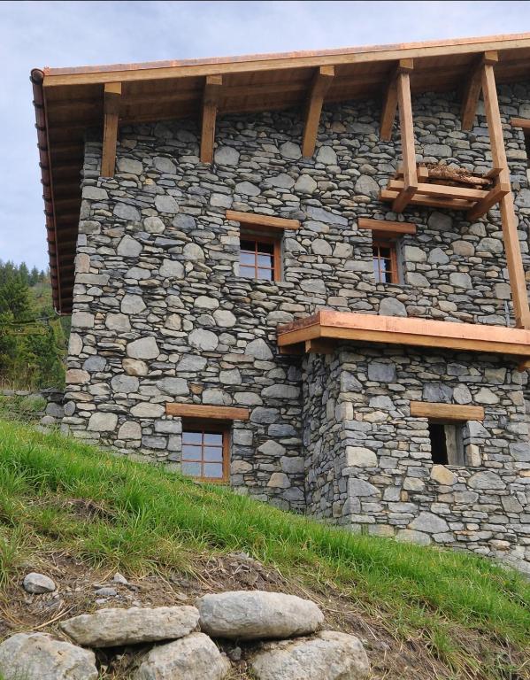 a stone building with a wooden roof on a hill at Les Chryolles - Les Marmottes in Valmeinier
