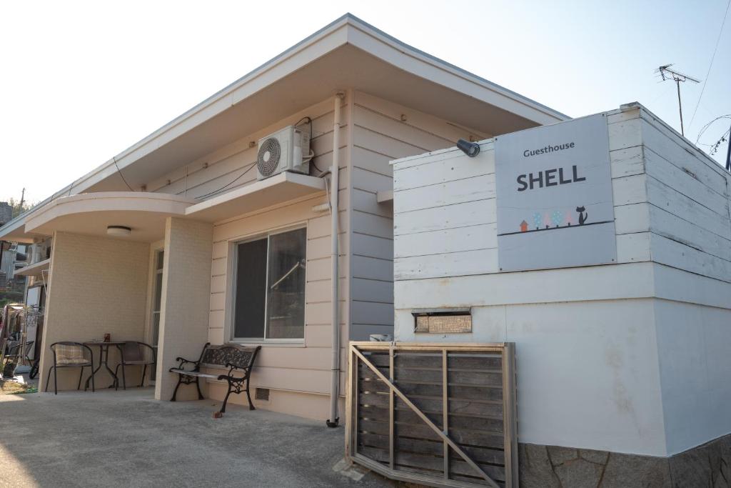 a small white building with a sign on it at Guesthouse SHELL in Naoshima