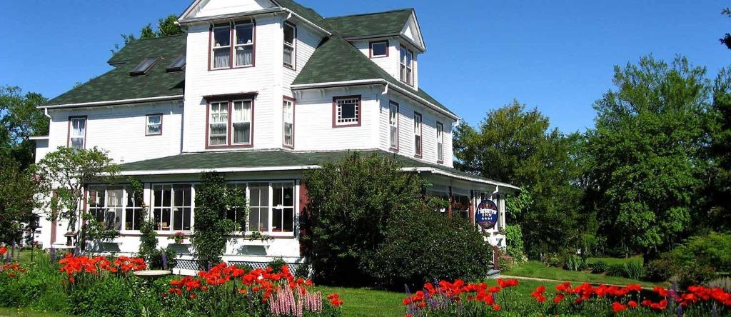 a large white house with flowers in front of it at Harbourview Inn in Smiths Cove