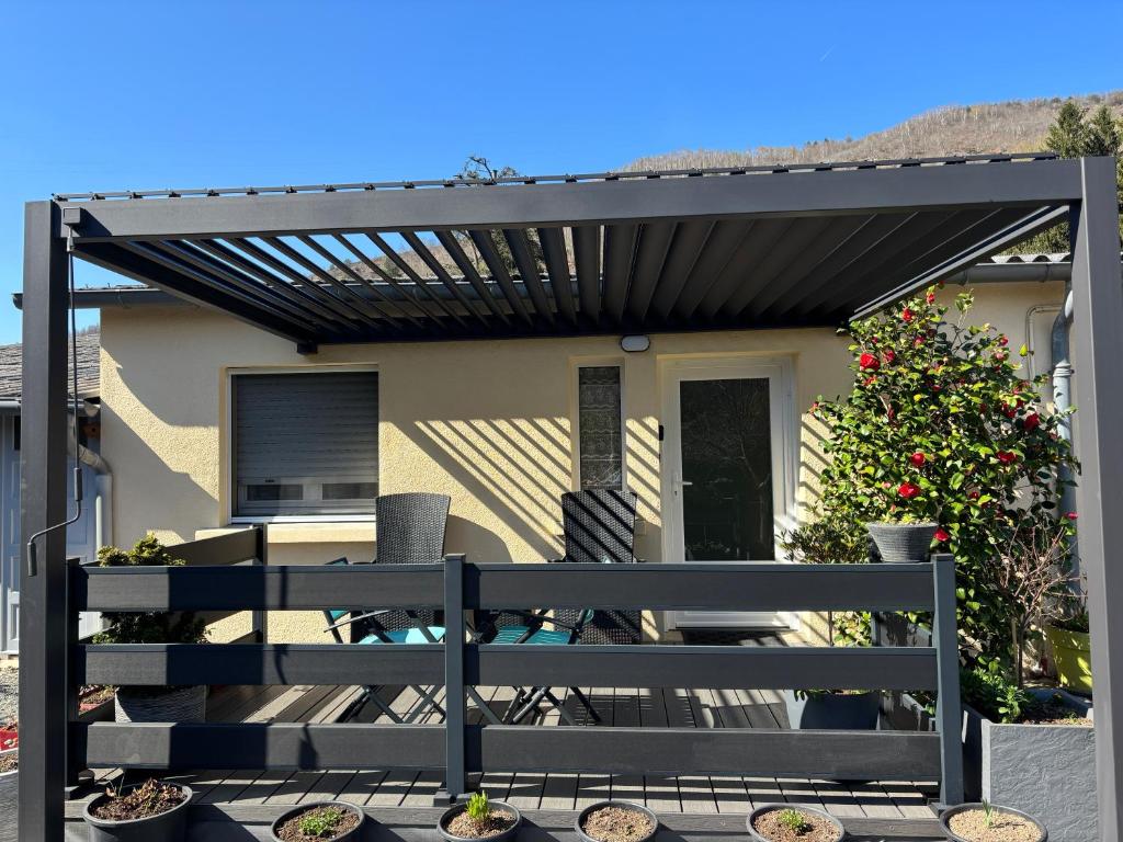 a black pergola on a house with a bench at Le Refuge d'Helix in Viviez