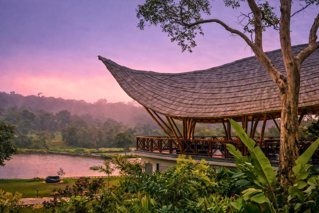 a pavilion with a roof next to a lake at The Leela Coorg Forest Sanctuary in Madikeri