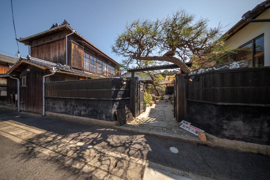 a fence in front of a house with a tree at Oyajino Umi in Naoshima