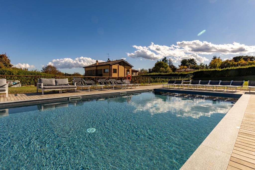 a swimming pool with chairs and a house in the background at Borgo Malvasia- La Quercia in Sasso Marconi