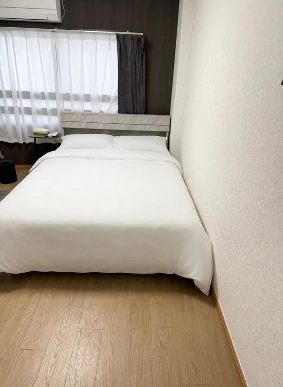 a large white bed in a room with a wooden floor at 亀井町Stay501 in Takamatsu