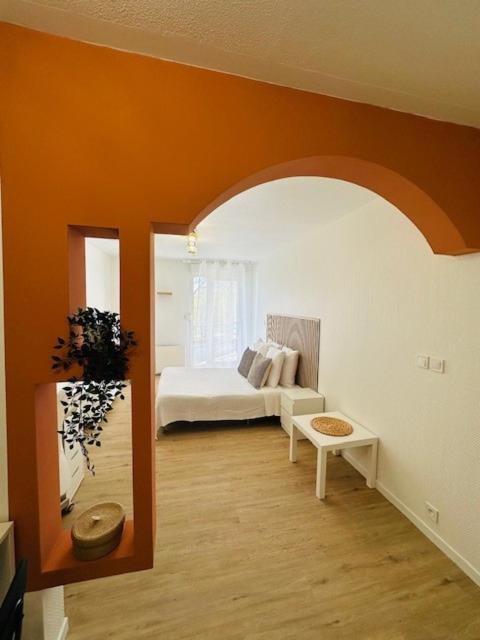 a living room with a bed and an orange wall at Sphinx Résidences - Tempologis Mémorial in Caen