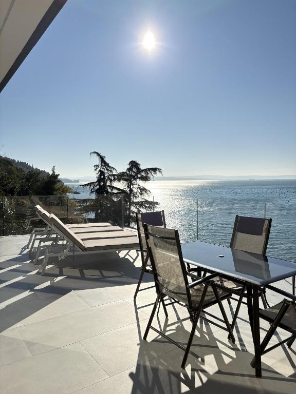 a group of tables and chairs on a patio overlooking the water at Seaside Escape in Trieste