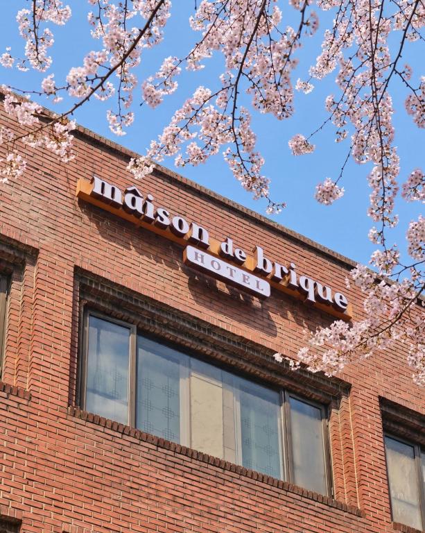 a sign on the side of a brick building with pink flowers at 메종드브릭 호텔 in Seoul