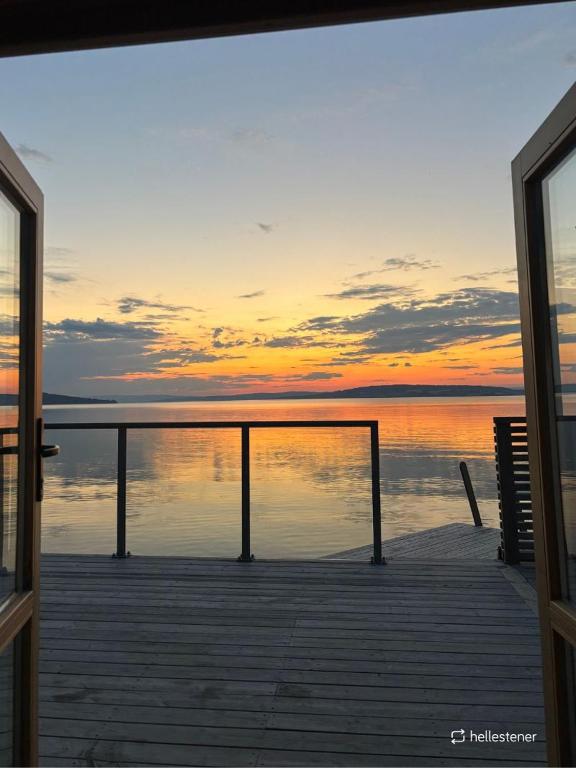 a dock with a view of the ocean at sunset at Idylliske Evjua ved Mjøsa in Skreia