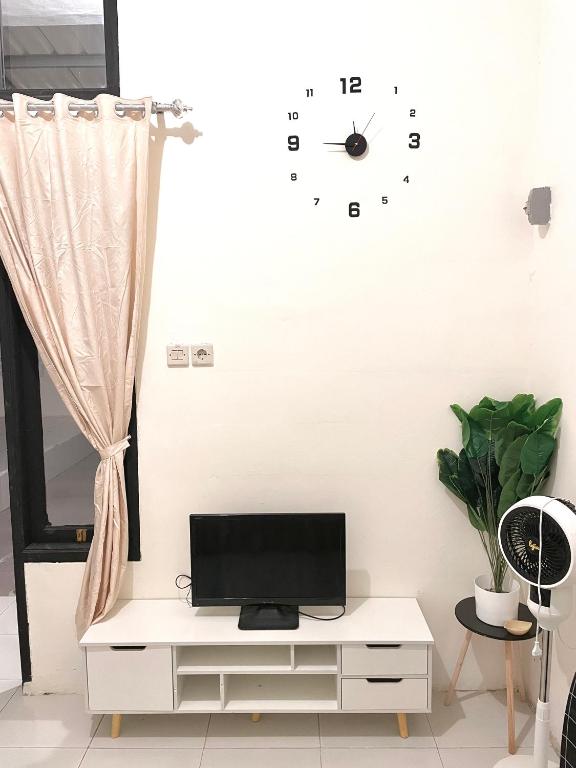 a living room with a tv and a clock on the wall at Ibiza house pangandaran in Pangandaran