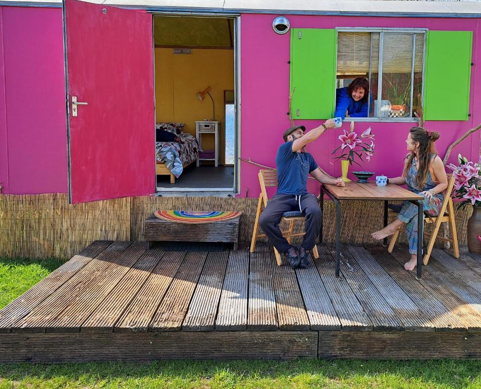 a group of people sitting at a table outside a house at Pipowagen Doe Maar Roze in Bant