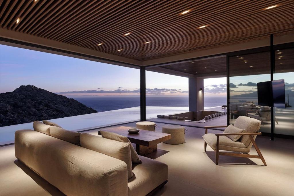 a living room with a couch and chairs and a television at Crimson View Villa by Hide Out in Ios Chora