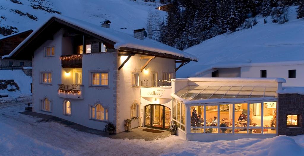 Une grande maison blanche dans la neige la nuit dans l'établissement B&B Appartments Cudlea, à Selva di Val Gardena