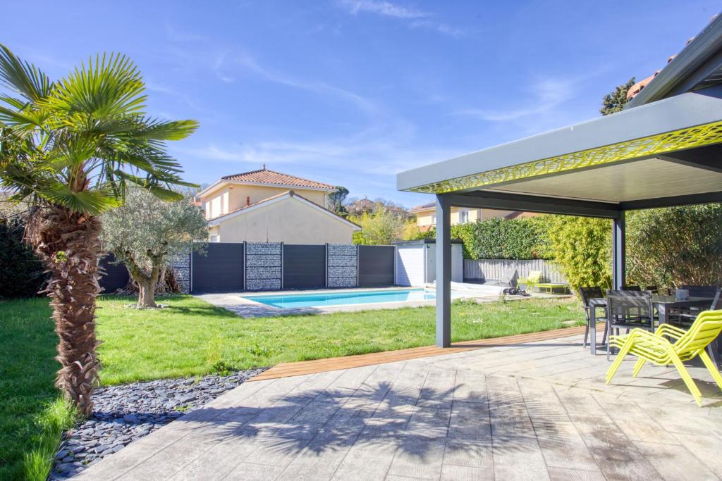 a patio with a table and chairs and a pool at Superbe Villa, 4 chambres, parking, garage et piscine in Genas