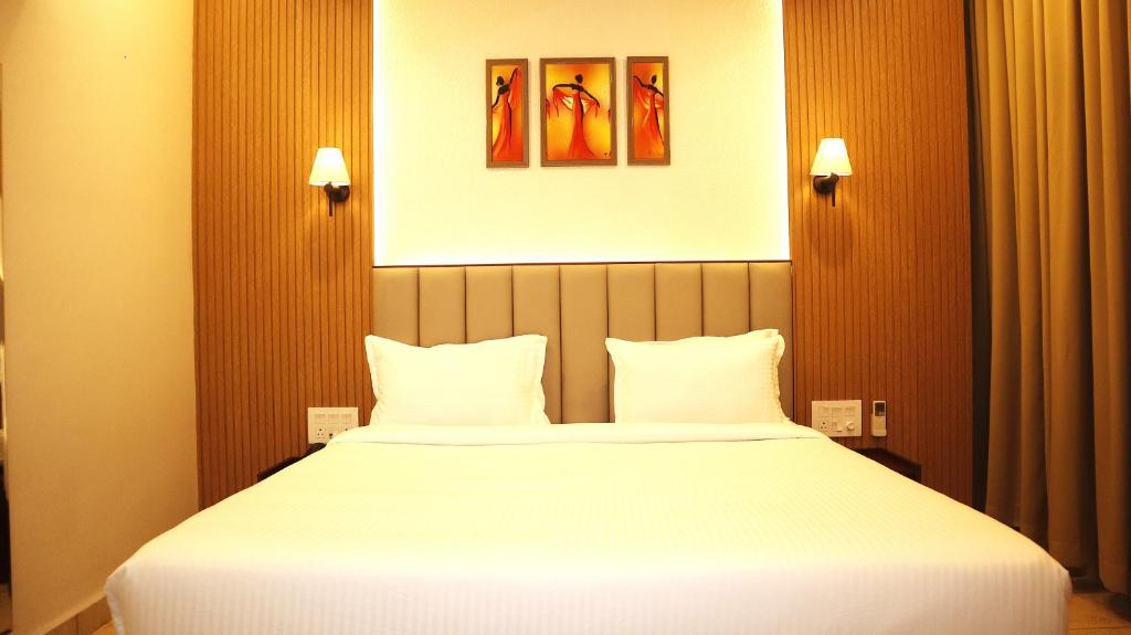 a bedroom with a large white bed with two pillows at Narmada Residency in Hubli