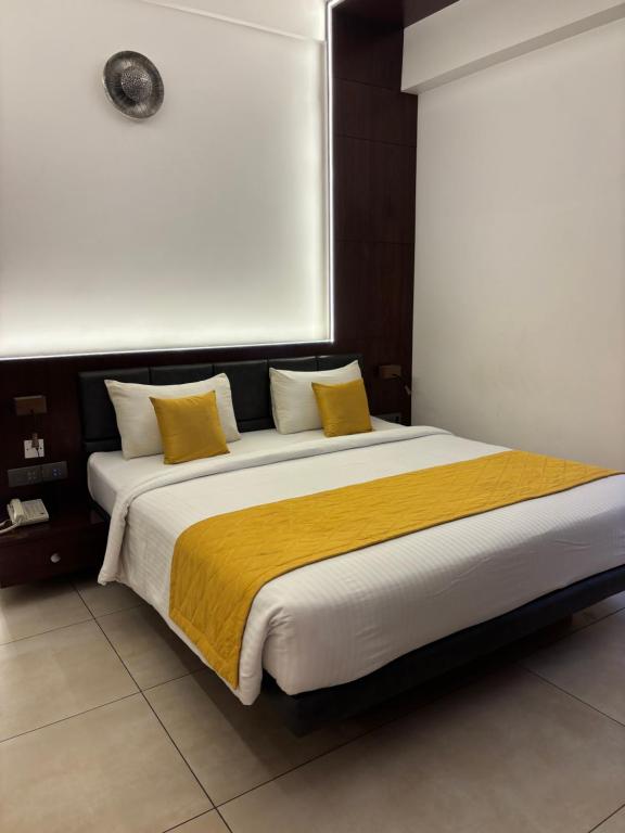 a bedroom with a large bed with yellow pillows at SRS Suites in Bangalore