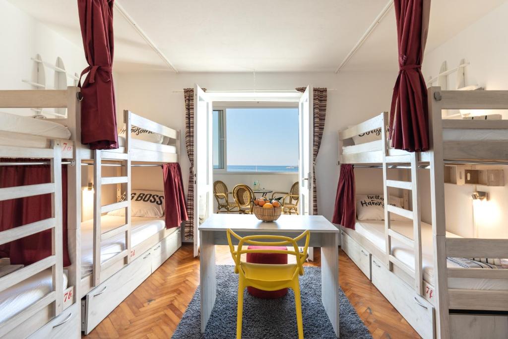 a bedroom with bunk beds and a desk with a yellow chair at Hostel Casa La Cha in Novalja