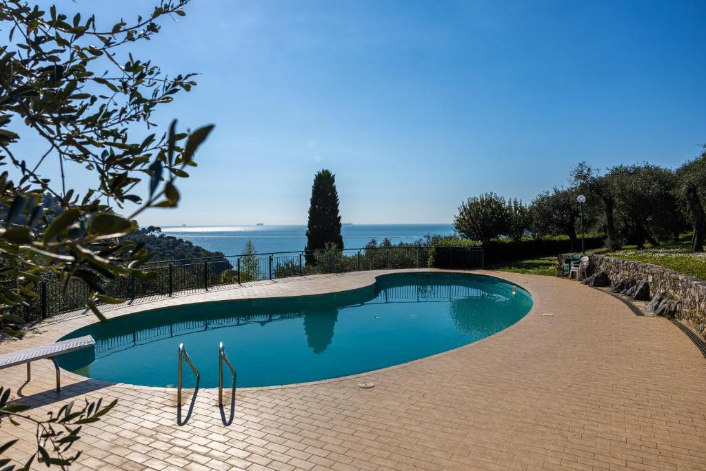 a swimming pool on a brick walkway next to the ocean at La Caletta Di Luce in Lerici