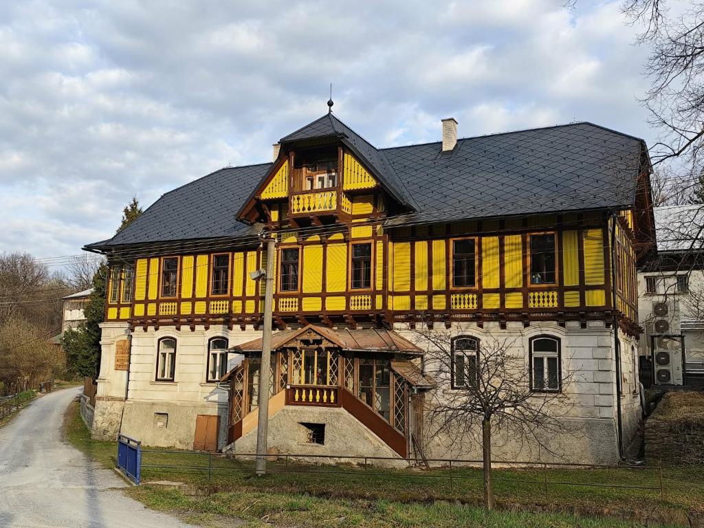 a yellow and white house with a black roof at středisko Doubrava in Zlaté Hory