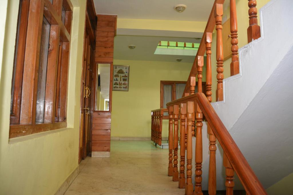 a hallway with a wooden staircase in a house at AbodeHome Cottage in Manāli