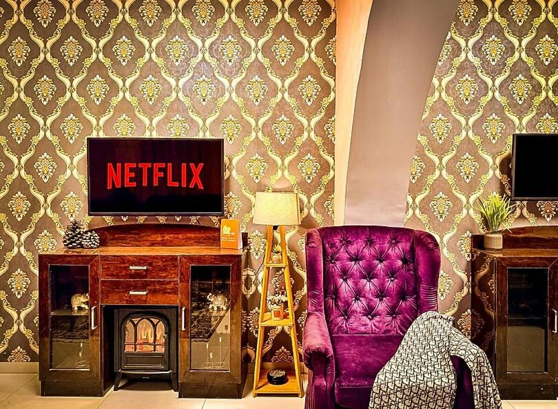 a living room with a tv and a chair at The Bay Leaf Resort in Shimla