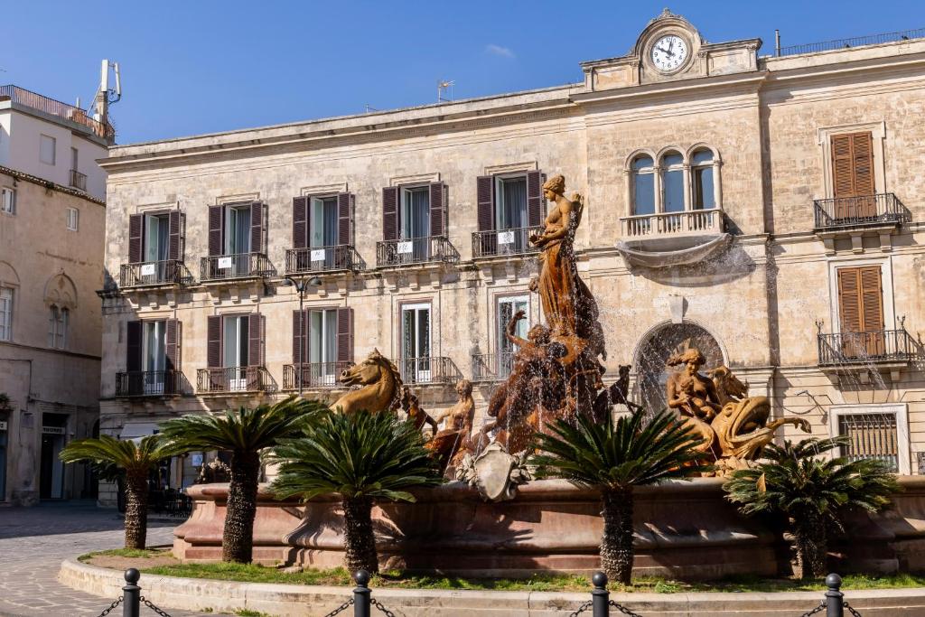 a fountain in front of a building with a statue at Archimede Charm B&B - Historical Palace in Ortigia in Syracuse