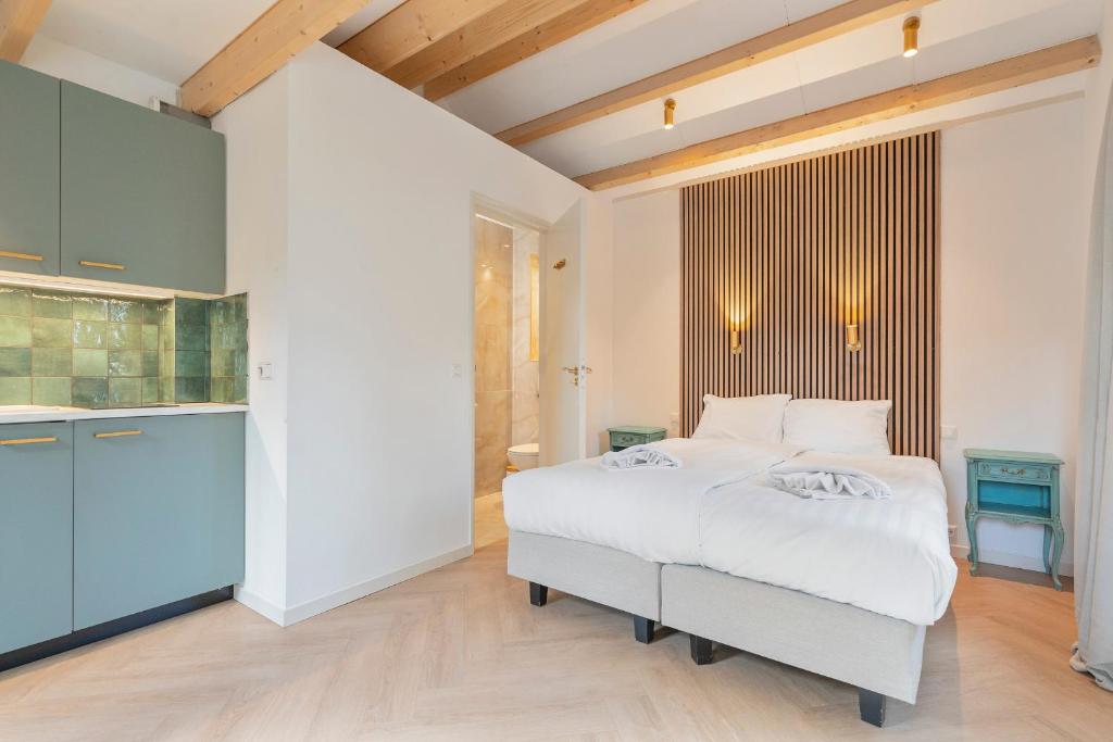 a bedroom with a white bed and a kitchen at Studio Oak & Studio Linde in Aerdenhout