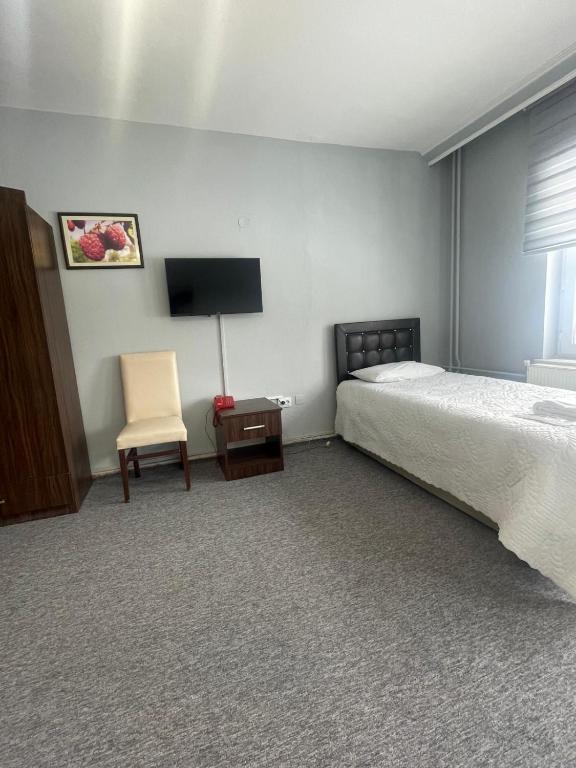 a bedroom with a bed and a chair and a television at zirve otel in Kumbet