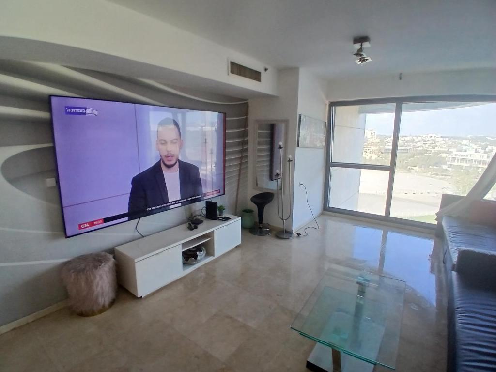 a living room with a large flat screen tv on the wall at מרינה טוורס מלון בוטיק in Herzliya B