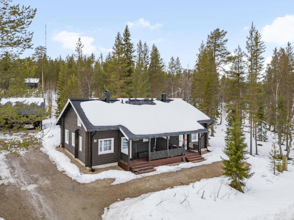 a house in the woods with snow on the roof at Skicamp 3 - Modern 3BR Villa in Pyhätunturi in Pyhätunturi