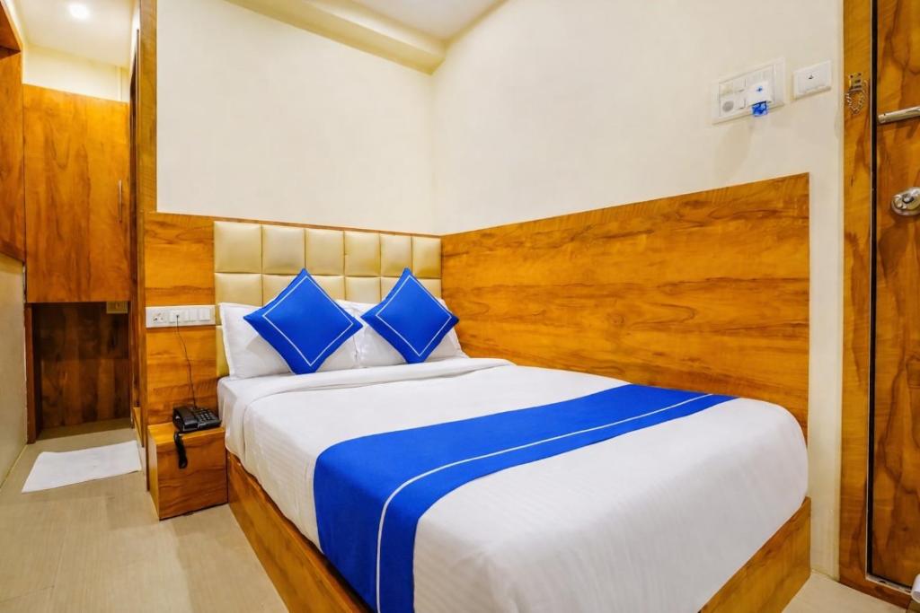 a bedroom with a large bed with blue pillows at Hotel Indore Palace Nagpada in Mumbai