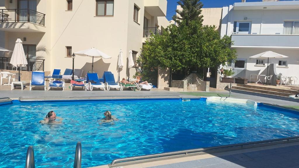 two people swimming in a swimming pool in a building at C & A Hotel Apartments in Polis Chrysochous