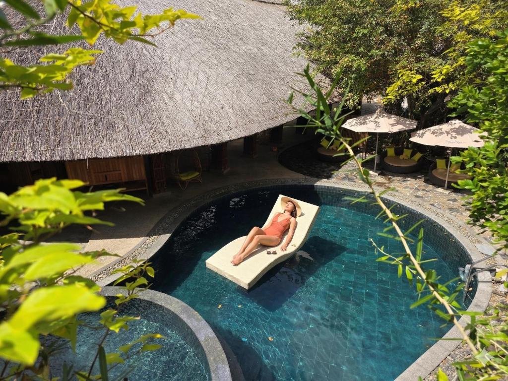 a woman laying on a raft in a swimming pool at MissBamboo Hotel Nha Trang in Nha Trang