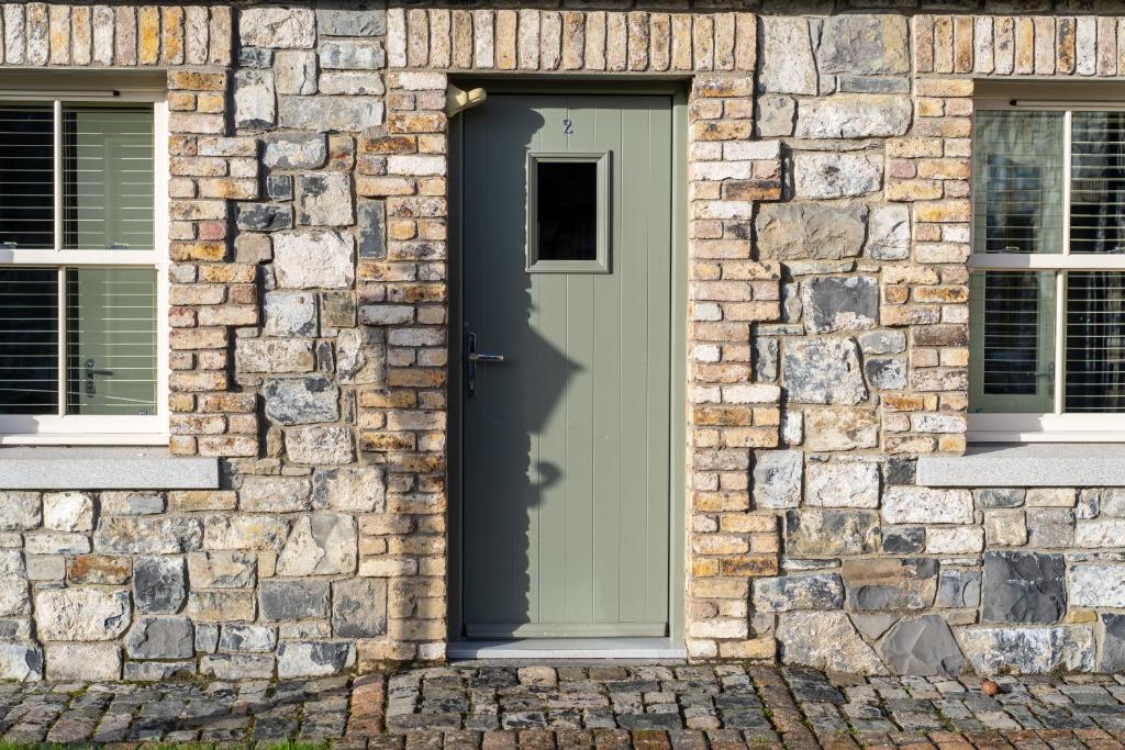 a green door on a stone building with two windows at Alensgrove Cottages #2 in Leixlip