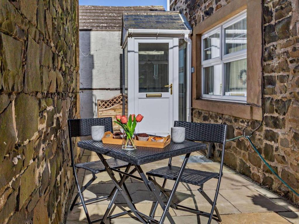 a table with two chairs and flowers on a patio at 1 Bed in Alnwick oc-94380 in Embleton