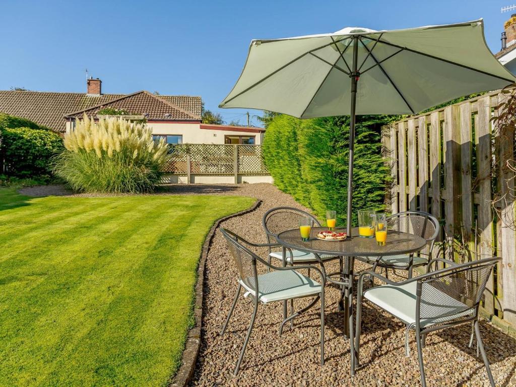 a table and chairs with an umbrella in a yard at 3 Bed in Wooler oc-93544 in Wooler