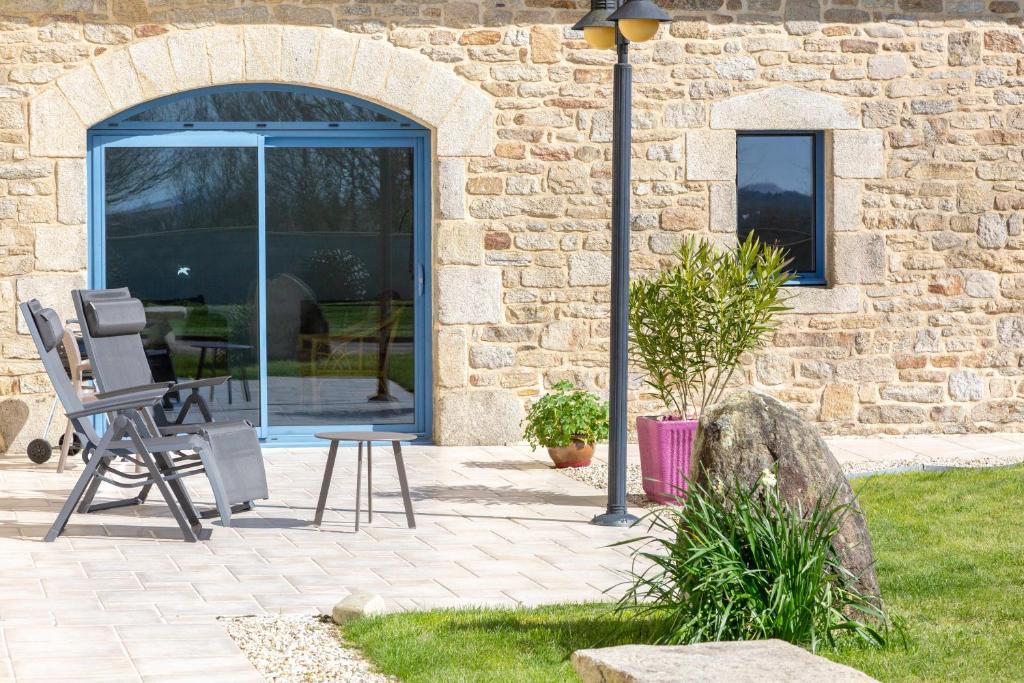 a patio with two chairs and a table in front of a building at Maison Indépendante Sur Jardin in Mahalon