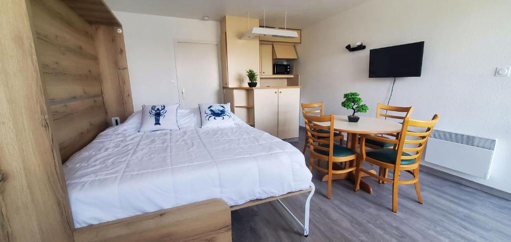 a bedroom with a bed and a table and chairs at BLEUE OCEANE - Studio, Piscine commune - U65 in Carnac