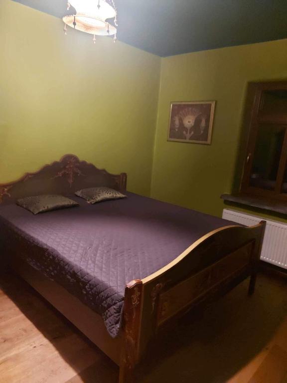 a bedroom with a bed with purple sheets and green walls at Balto kalno namai, Kernavėje in Kernavė